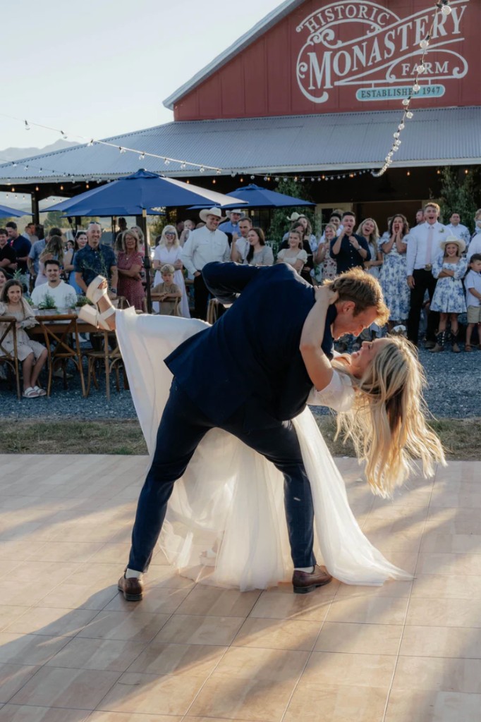 Bride and groom dancing at an outdoor reception in front of the Historic Monastery Farm barn